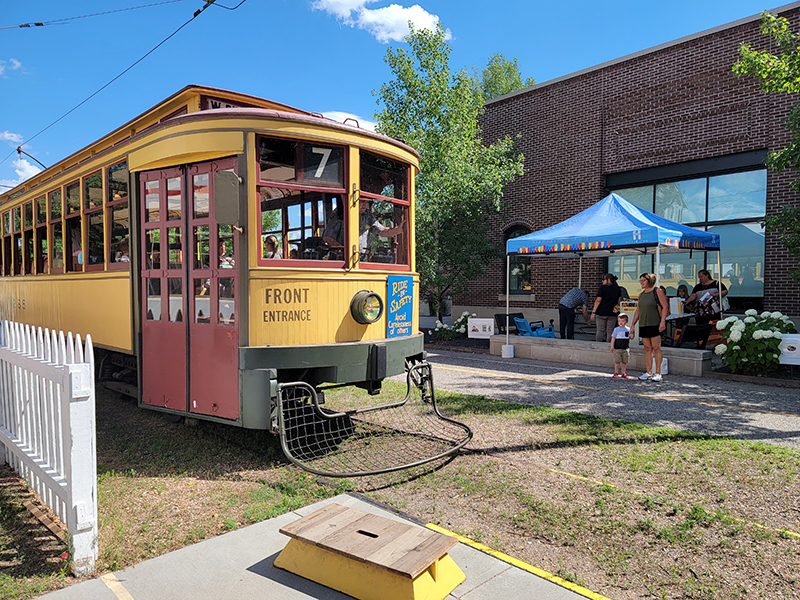 A photo of a streetcar running next to the Excelsior Library.