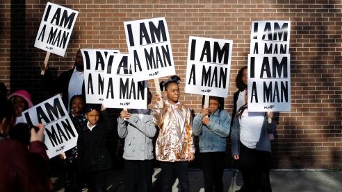 People of all ages holding signs that read I am a man