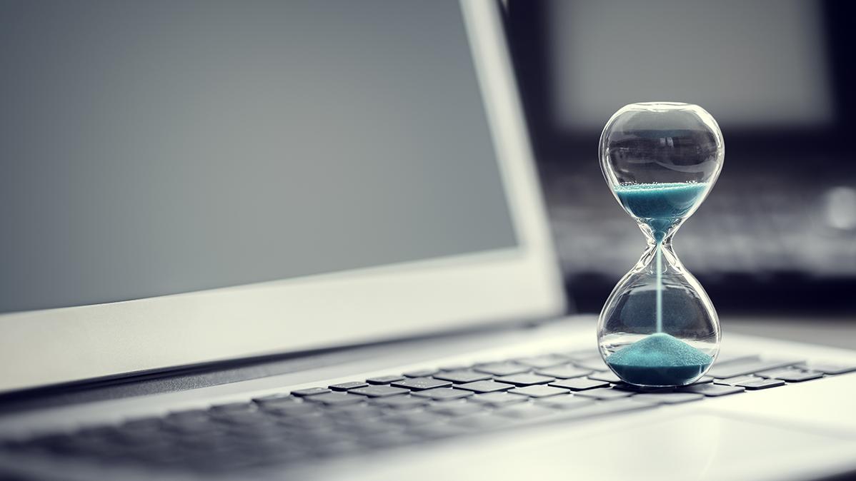 Hourglass running out of time on top of laptop