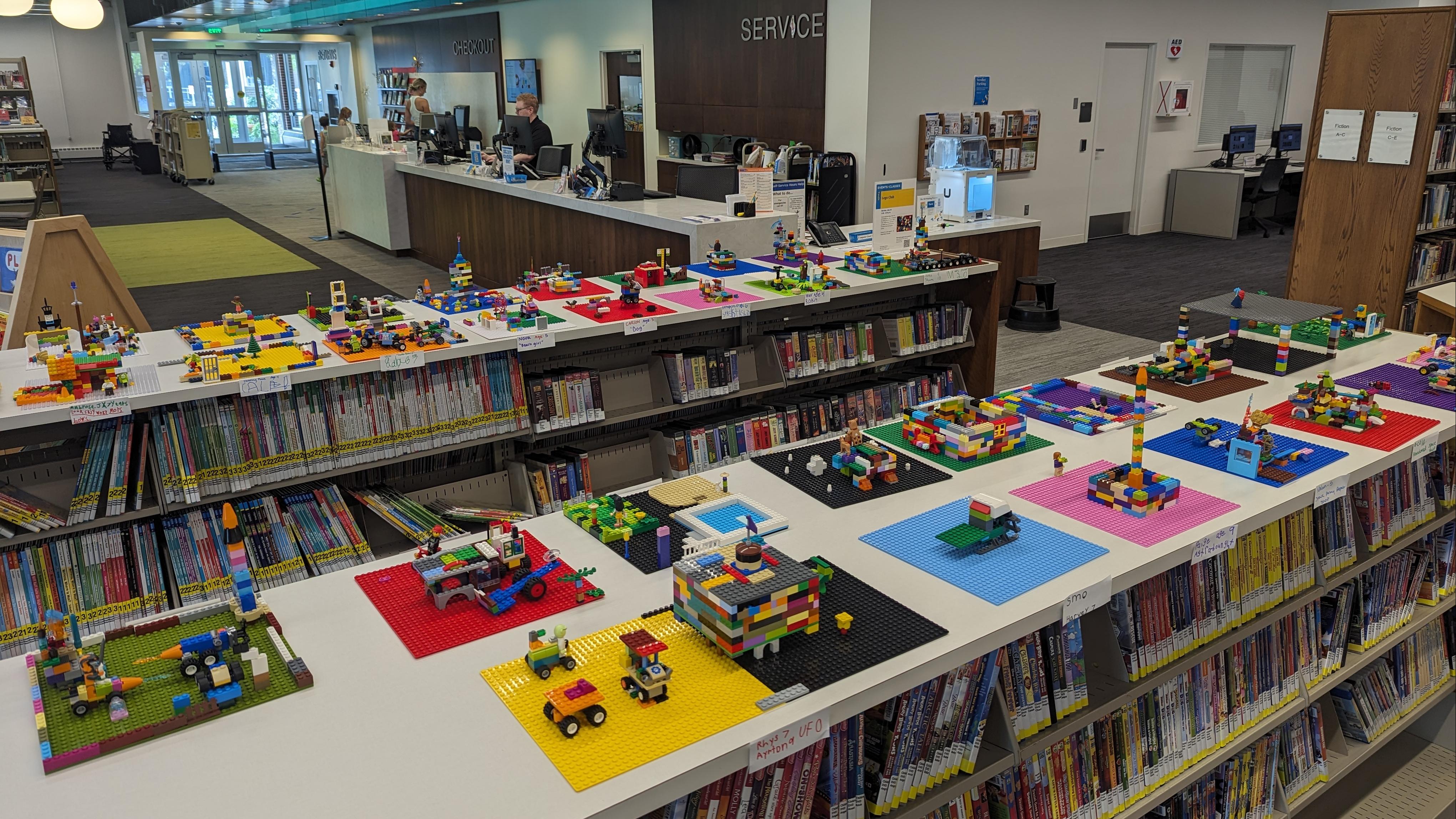 A photograph of dozens of Lego projects atop low bookshelves at Farmington Public Library.