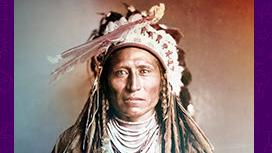 Indigenous man with feathered headdress and multiple white beaded necklaces