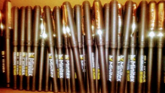 A photograph of dozens of new, black, Minitex pens.