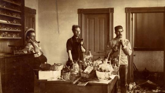 Three male students in a messy chemistry lab at Macalester College