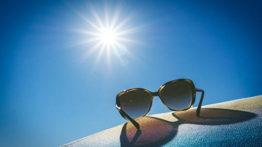 A photo of sunglasses with an elongated shadow from the bright sun.