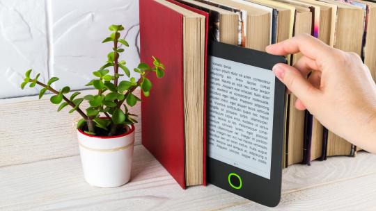 Tablet is pulled out from a row of shelved books