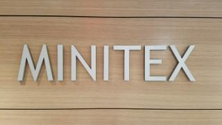 The "Minitex" sign in the entrance of Minitex's offices featuring silver all-caps lettering on a wood-panel background.