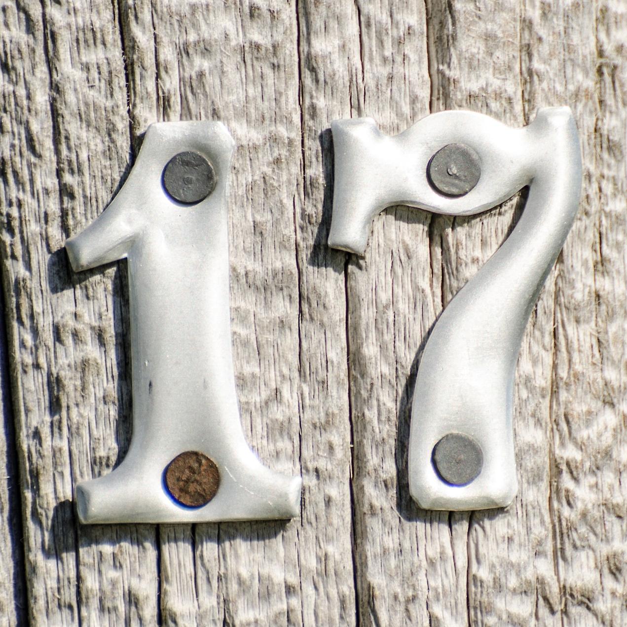 metallic number seventeen nailed to a wood surface