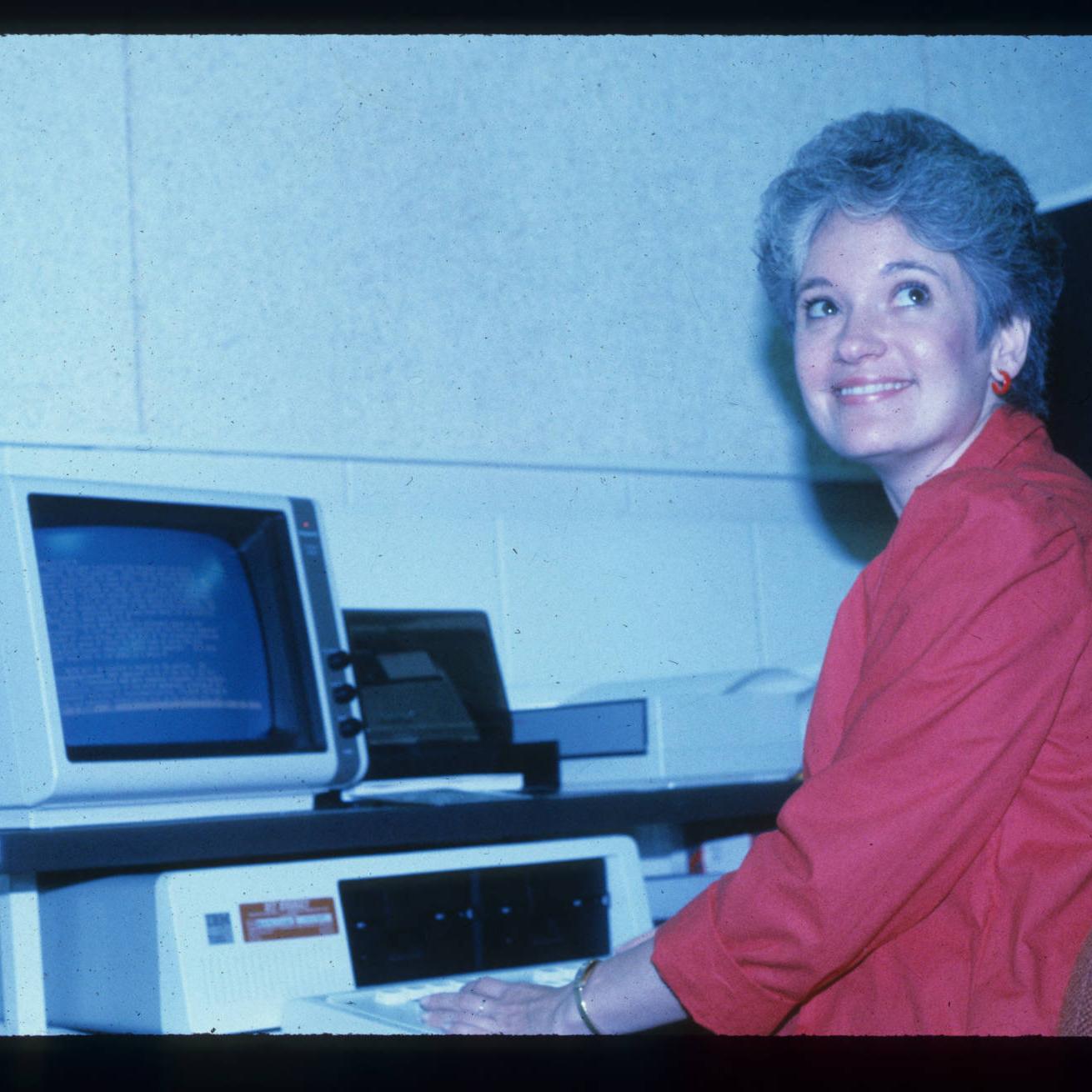 A photograph of former Minitex associate director Anita Branin sitting in front of the computer.