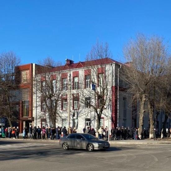 A photo of dozens of Ukranian people standing in line outside of a blood transfusion center.
