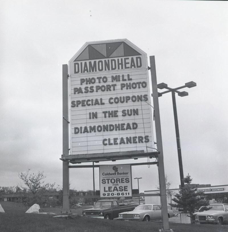 Large sign for Diamondhead Mall with text about passport photos, special coupons, and the Diamondhead Cleaners