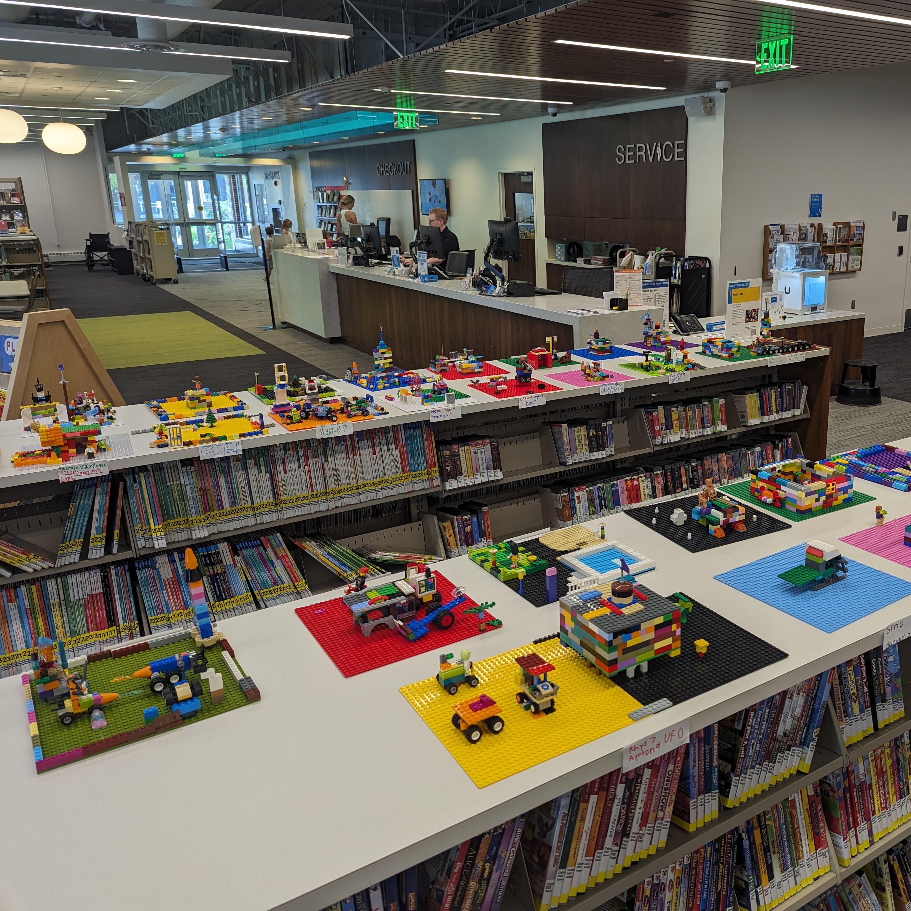 A photograph of dozens of Lego projects atop low bookshelves at Farmington Public Library.