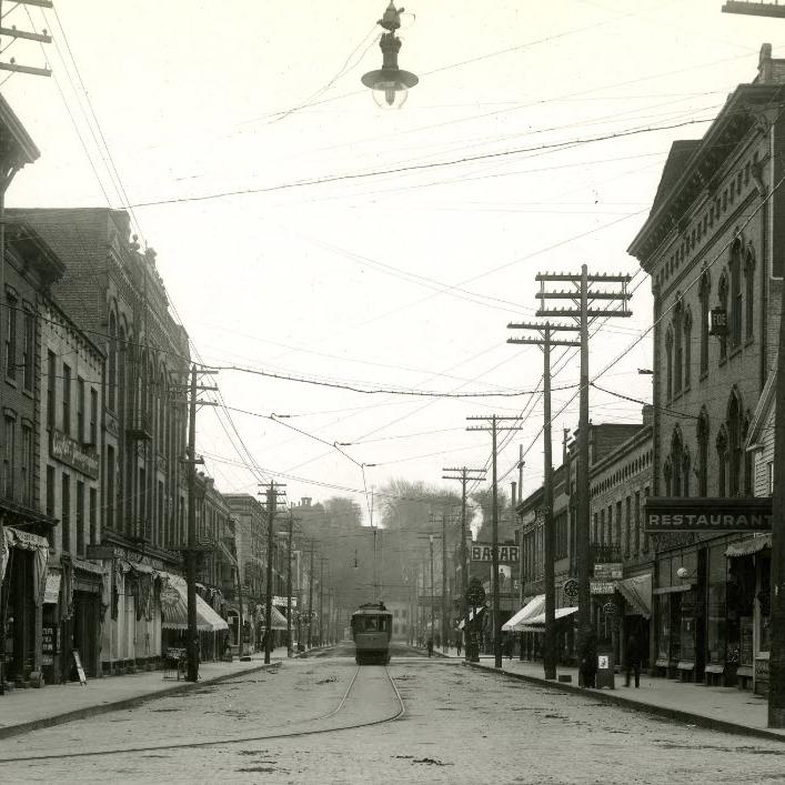 A streetcar runs down the middle of Main Street in Stillwater while buildings full of small businesses line each side of the road