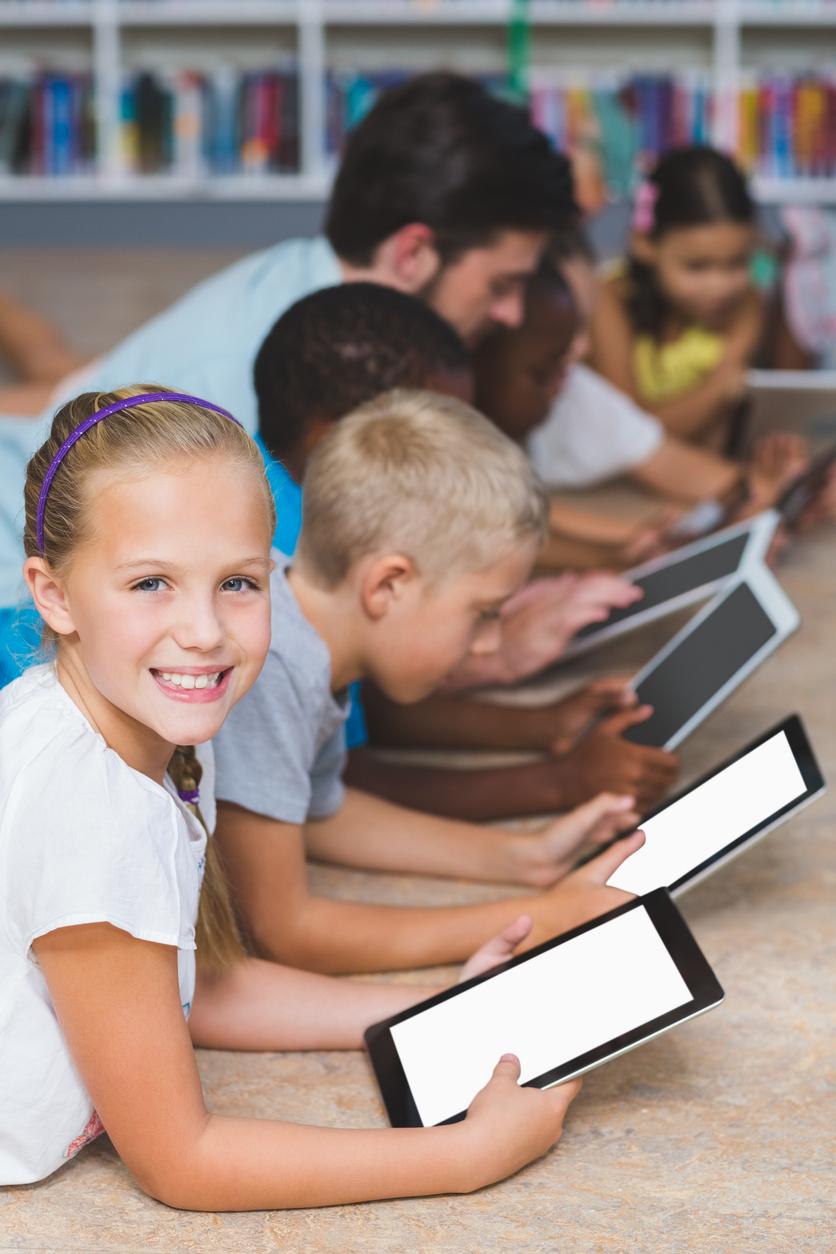 Elementary students reading from tablets